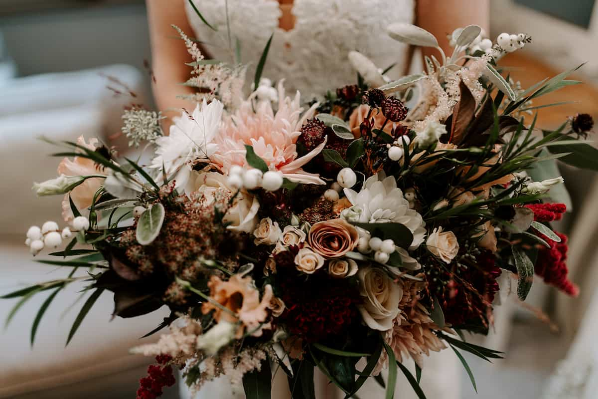 A bride holding a textured bouquet with pink flowers