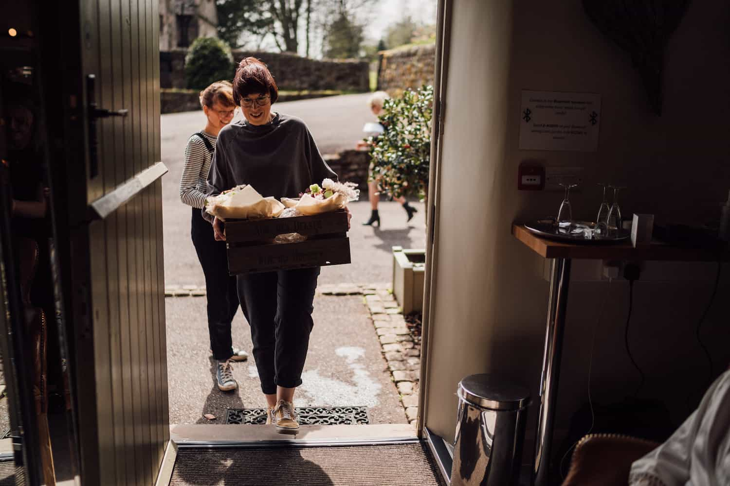 Smiling florists wait at the doorway with a flower delivery.