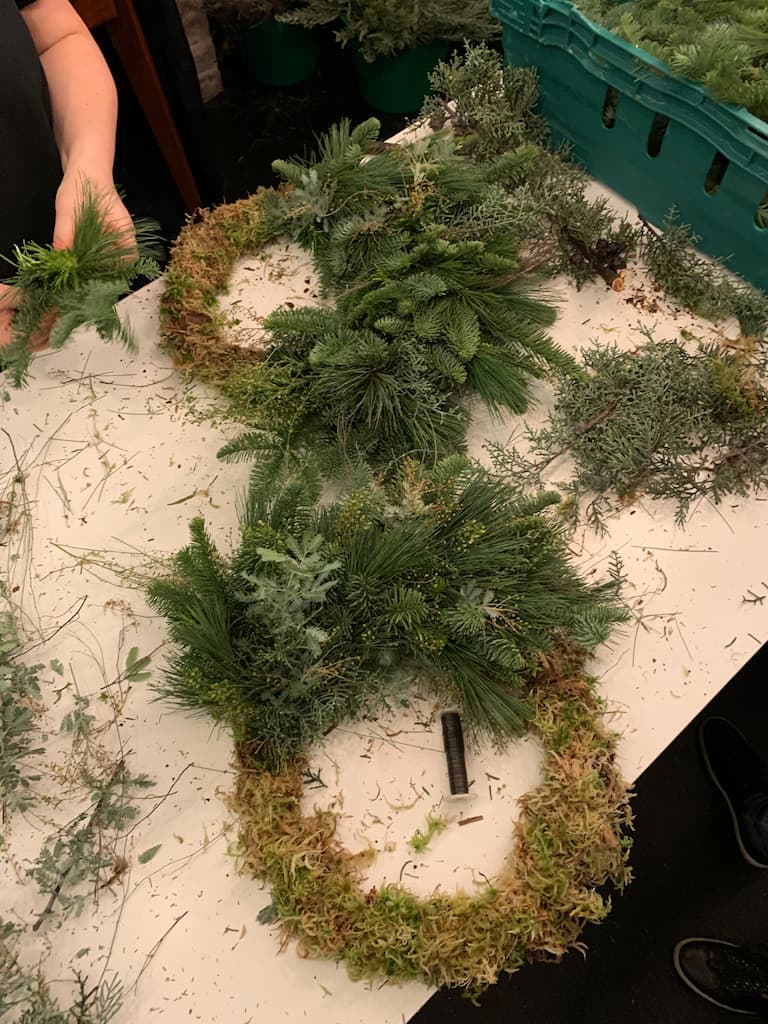 Partly finished Christmas wreaths lie on a table